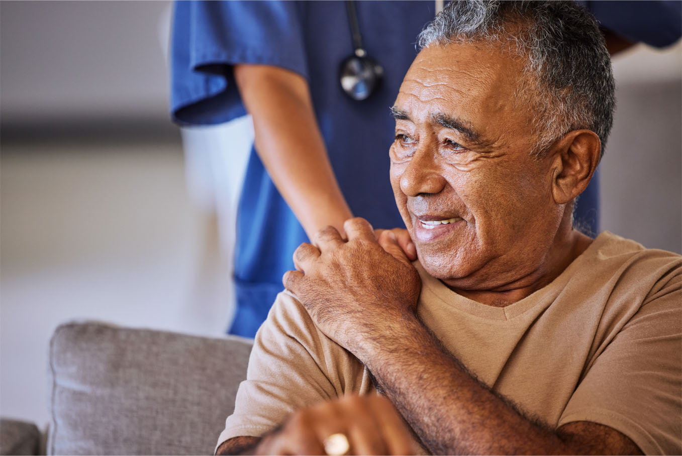 A senior man holds the hand of a medical provider assisting him with bloodwork.